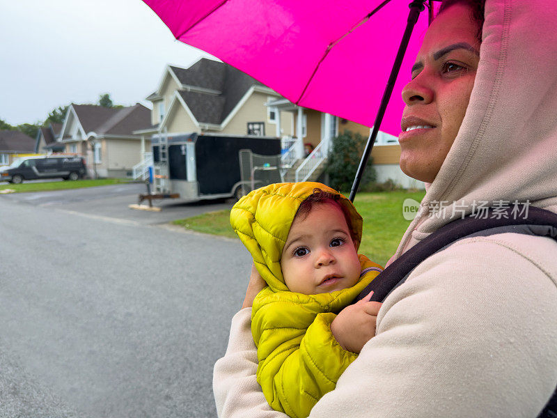 母女俩撑着伞在雨中散步