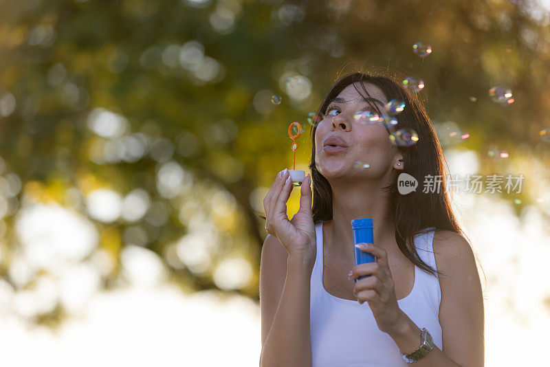 年轻女子正在外面吹泡泡。