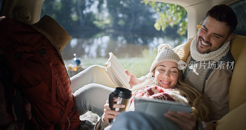 露营车，平板电脑和快乐的情侣阅读，流媒体和观看在线露营，结合和放松。网站，电子书故事和浪漫的人休息在SUV，汽车或停车场露营地