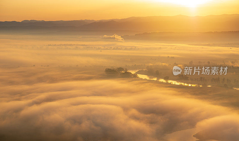 鸟瞰在美丽的清晨薄雾在高原山谷的日出。低低的云和雾笼罩着沉睡的草地。丘陵山谷雾霭景观。宁静的乡村时光