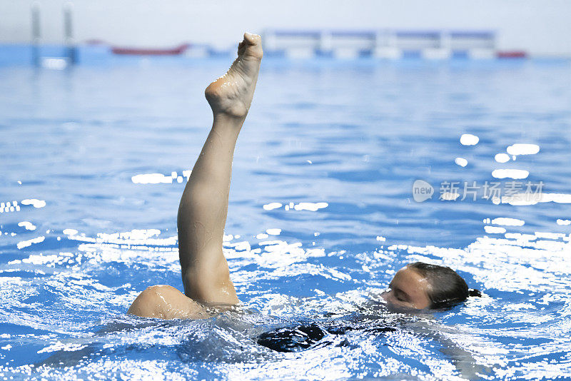 花样游泳女运动员独自在游泳池的水中练习新动作