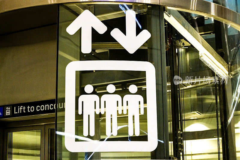电梯标识用三个人和两个箭头画在电梯的玻璃墙上，背景用复制空间的玻璃墙