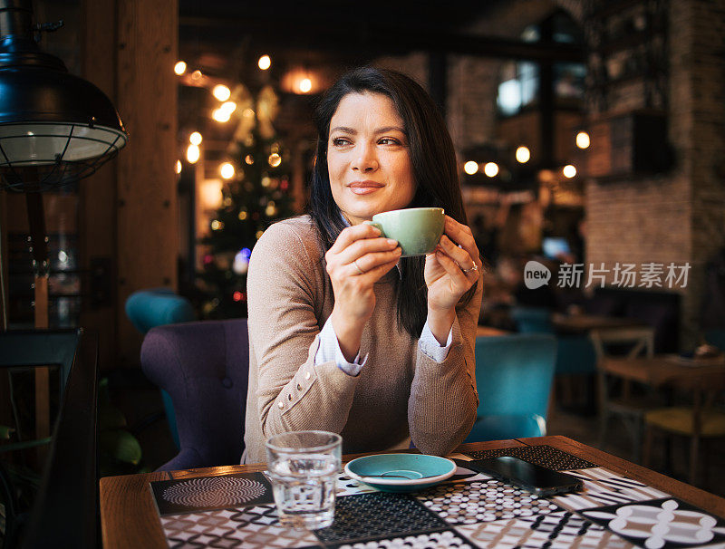 一位漂亮的年轻女子坐在酒吧里喝咖啡