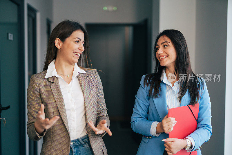 两个年轻的女商人在商业走廊里聊天