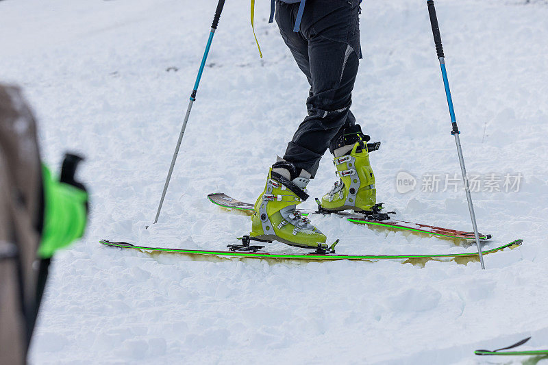 一个人在滑雪旅行或登山时表演180度转弯的细节。一个人在滑雪板上转弯向山上走。