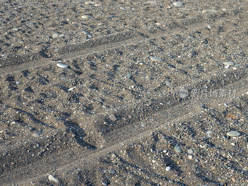 在沙地上车辙。沙滩上的车轮留下的痕迹。沙子和石头。