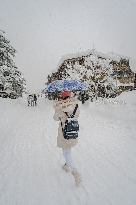 美丽的女游客享受他们的旅行白川古村在日本的冬天厚雪