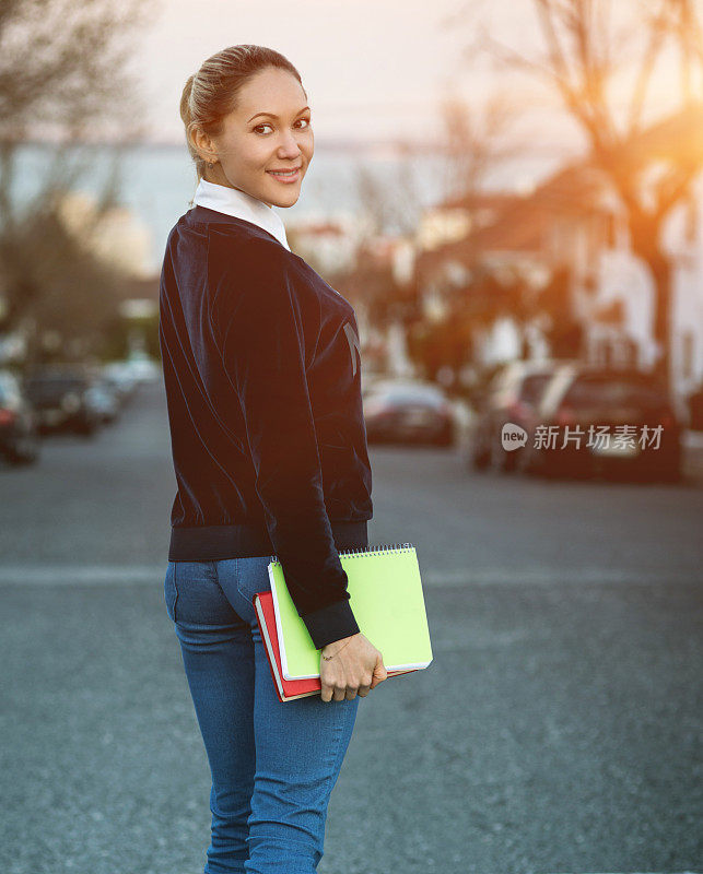 金发的学生女孩拿着书走着