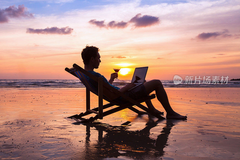 一个成功的商人在海滩上用笔记本电脑阅读电子邮件