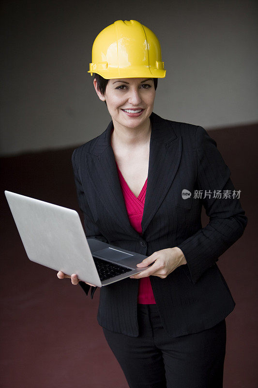 中年女性穿着西装，带着笔记本电脑和安全帽