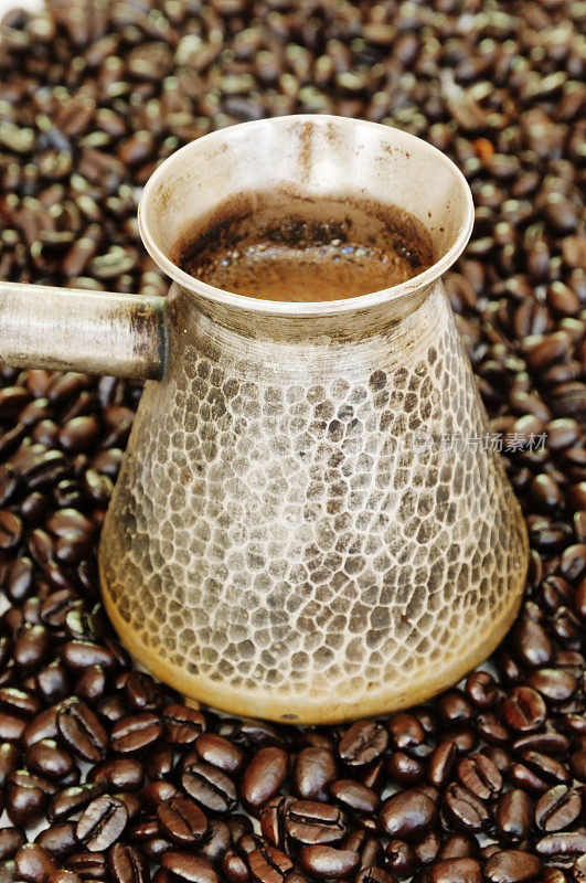 新鲜煮好的咖啡，周围是烘培的咖啡豆