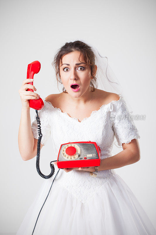 震惊的年轻新娘拿着旧的红色电话