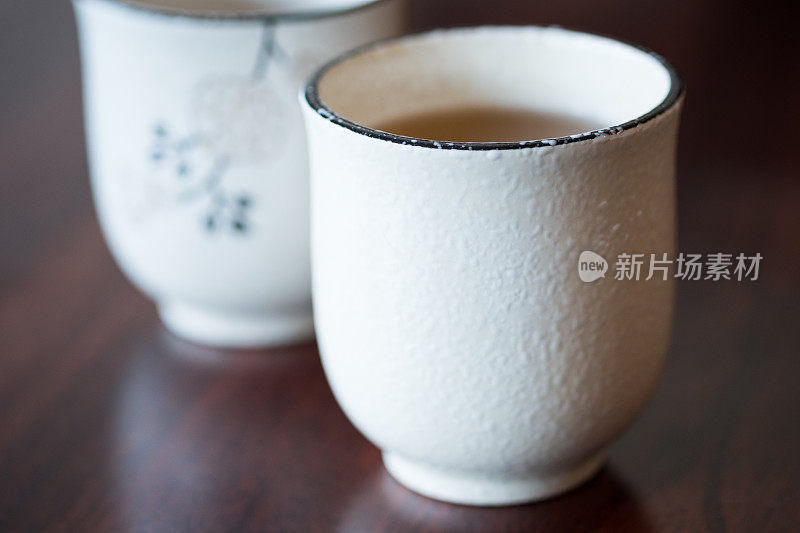 两个传统的白色日本茶杯与绿茶，木桌子