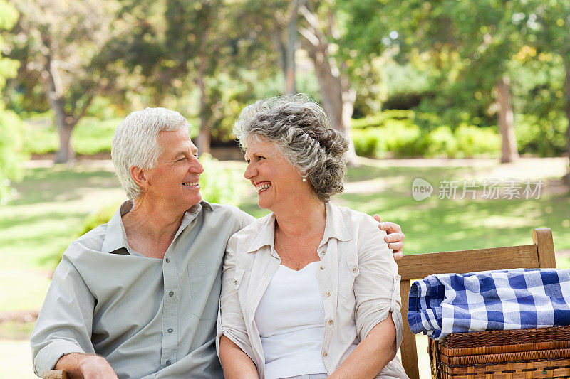 一对老夫妇拿着野餐篮互相微笑