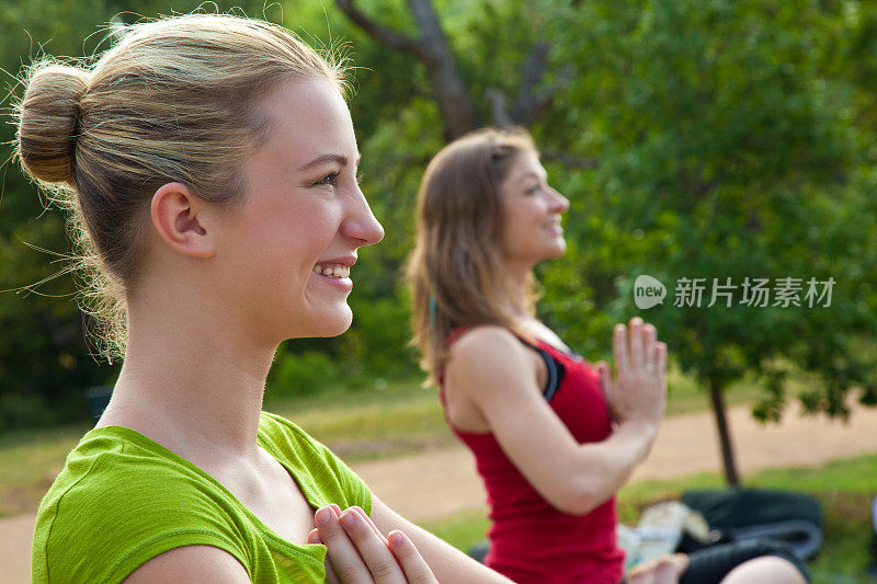 快乐的年轻女性在瑜伽姿势练习Acroyoga外面