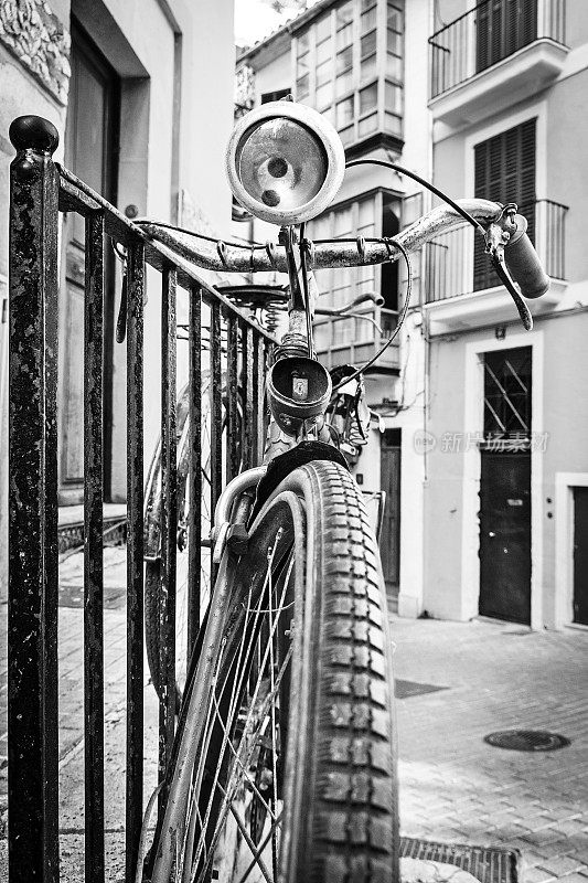 老旧生锈的自行车斜靠在老城的栏杆上。