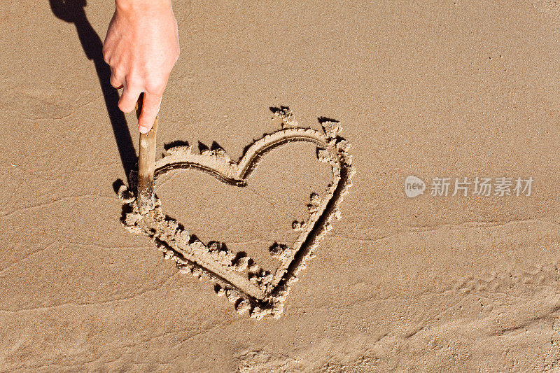 用手在沙子上画一颗心。