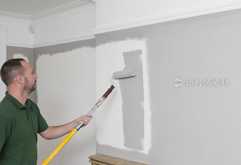 室内设计师用灰色油漆粉刷白色墙纸