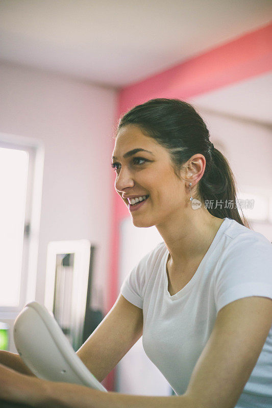 运动女人在一个健身俱乐部训练自行车-运动女孩在一个健身房的自行车上旋转