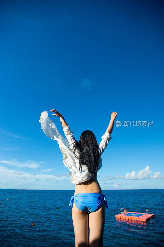 幸福的女人举起双手望着天空的大海