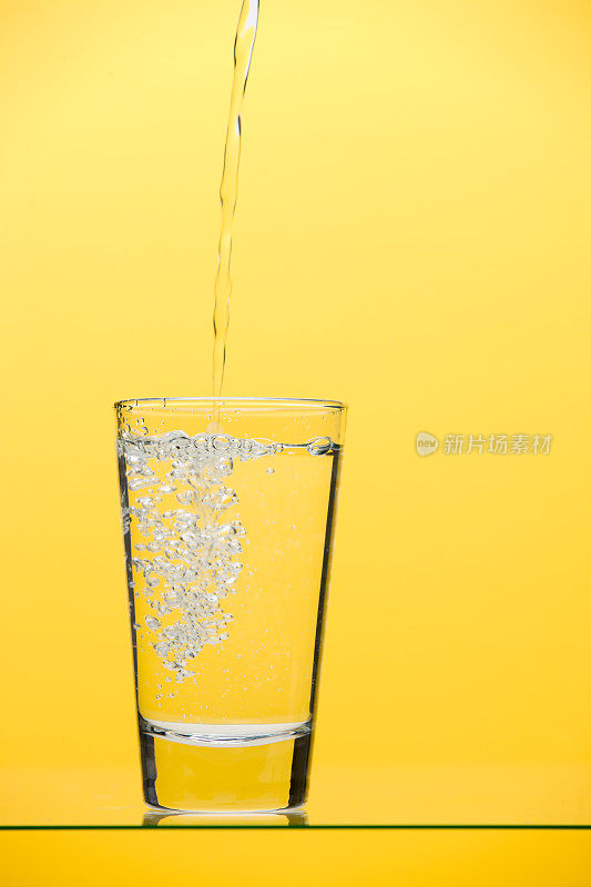 将饮用水倒入黄色的玻璃杯中