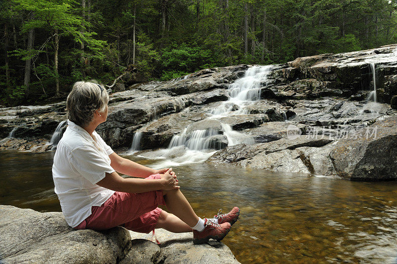 一名女子在瀑布附近放松，佛朗科尼亚峡谷州立公园，新罕布什尔州