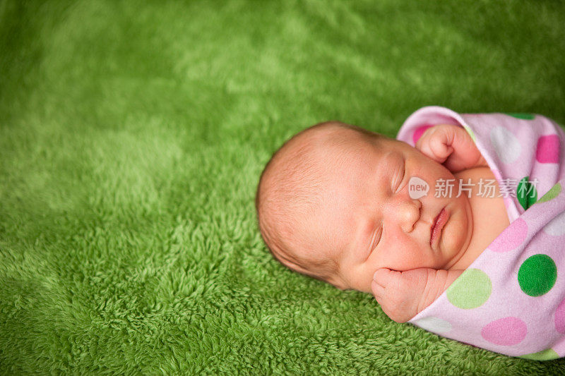 刚出生的女婴在圆点毯子里安静地睡觉