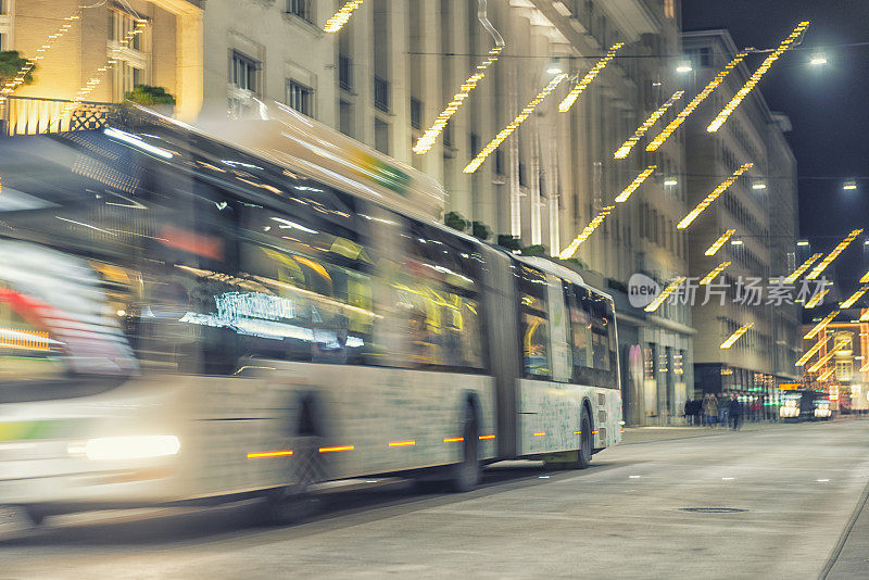城市巴士穿梭在灯火通明的城市街道上