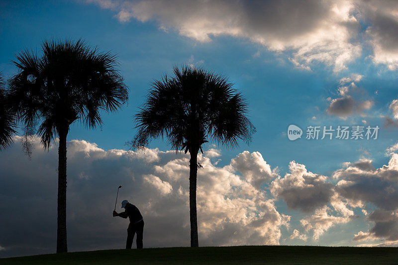 日出时高级高尔夫球手开球的剪影