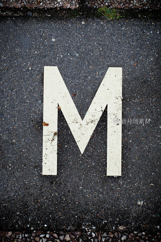 白色字母M在柏油路上。