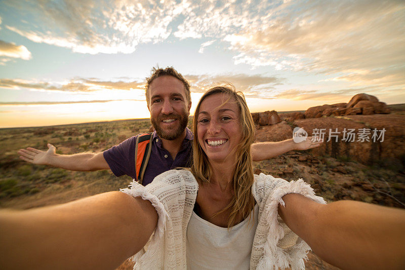 一对年轻夫妇在日出时与壮观的风景自拍
