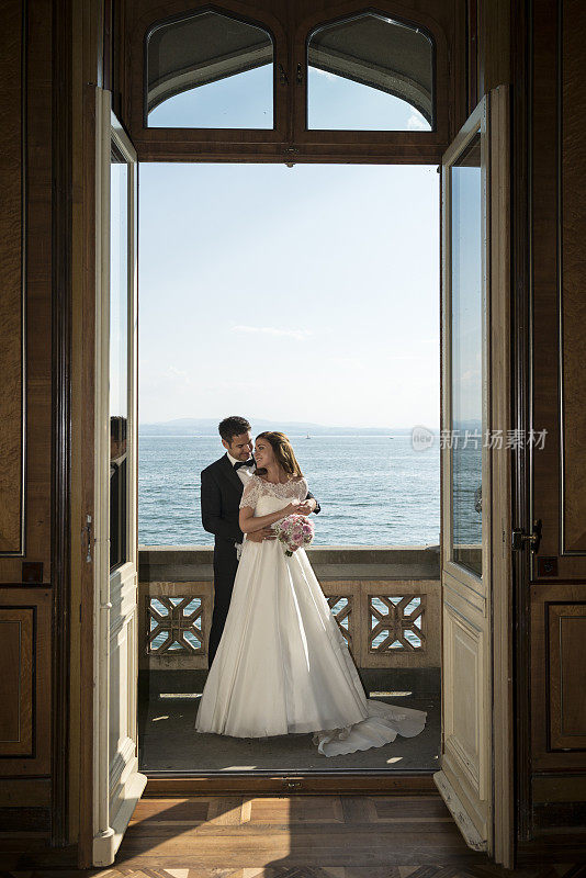 一对新婚夫妇站在老别墅的阳台上