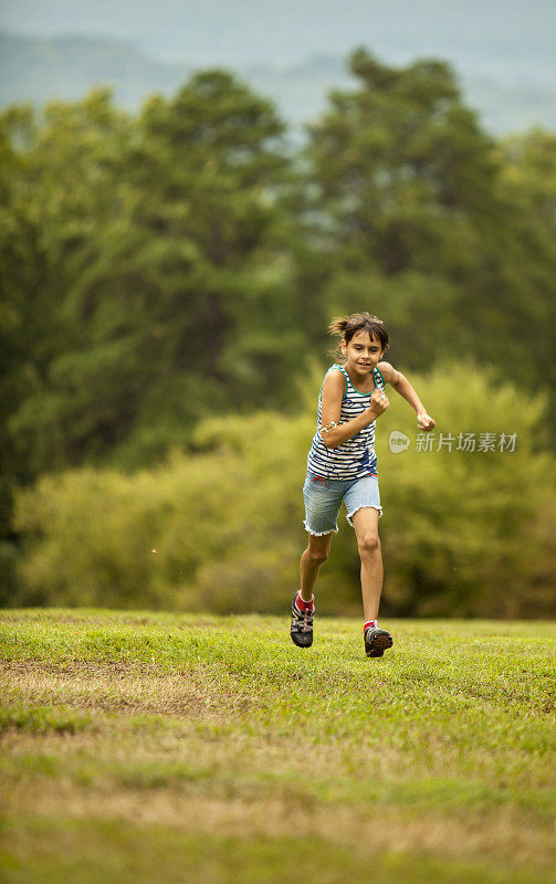 小女孩在夏日公园的草坪上奔跑