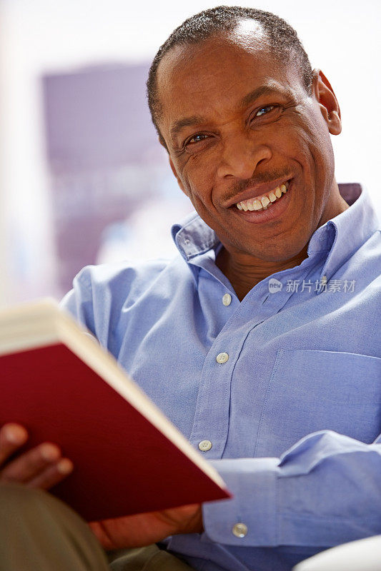 一个非洲人在读一本小说，对着你微笑