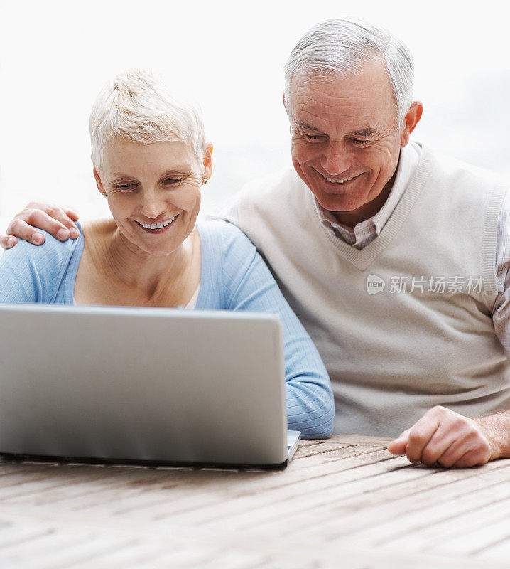 微笑的老年男女使用笔记本电脑