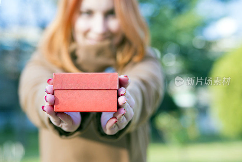 女人拿着一个红色礼品盒表示赠送