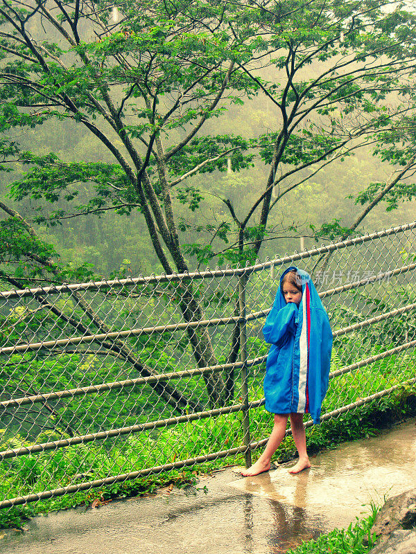 女孩穿着超大号雨衣，赤脚在夏威夷瀑布公园