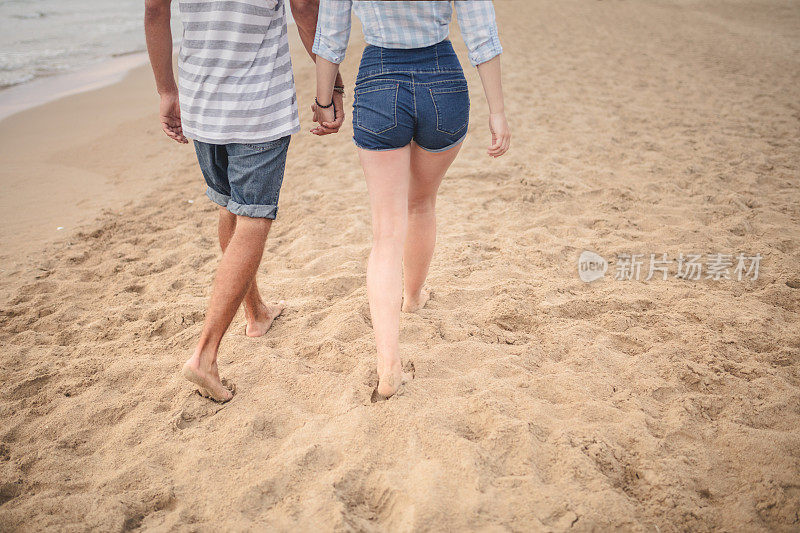 一对情侣手牵着手在海滩上散步
