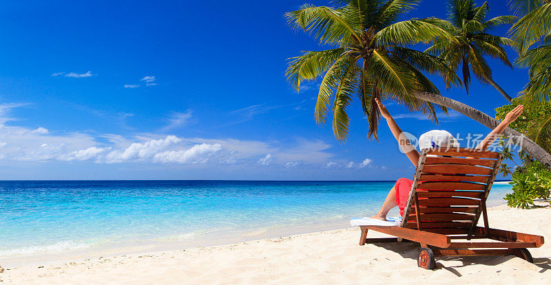 快乐的年轻女子坐在海滩的椅子上