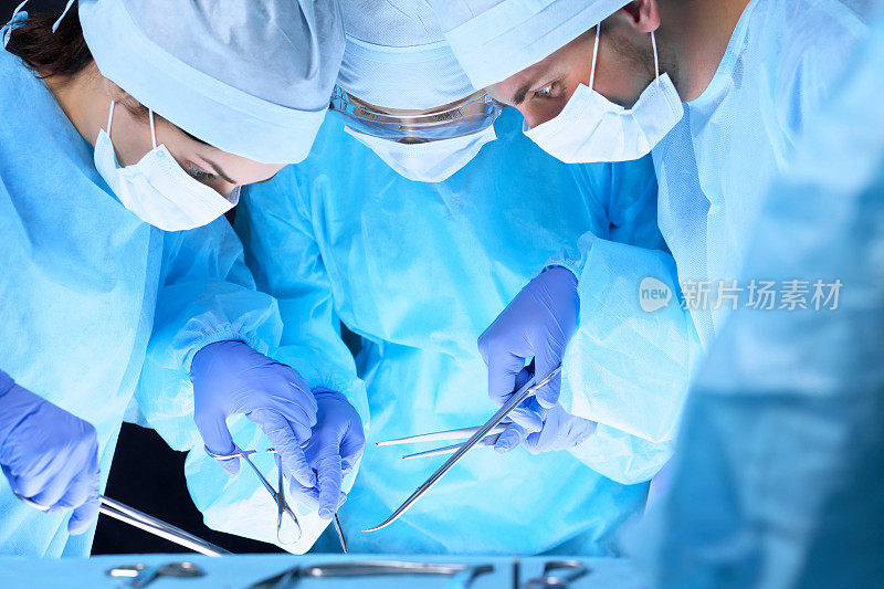 医疗队进行手术一组在手术室工作的外科医生，色调为蓝色