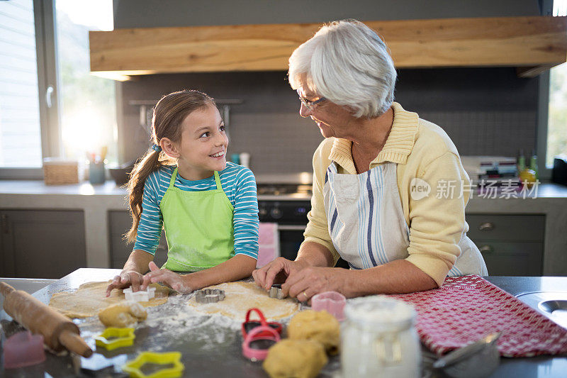 祖母和孙女用饼干切割机切面团