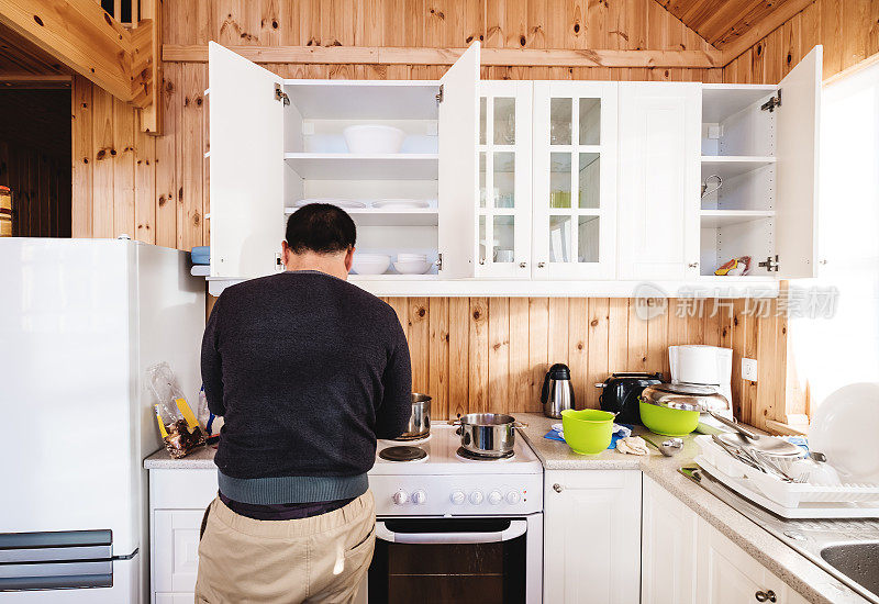 后视图一个男人在厨房准备早餐，在早上