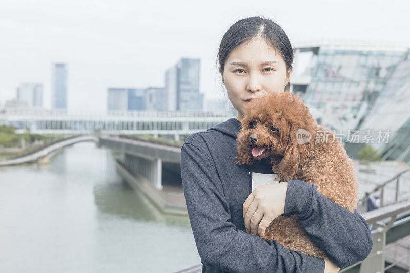 一个女人抱着她的宠物站在桥上看风景