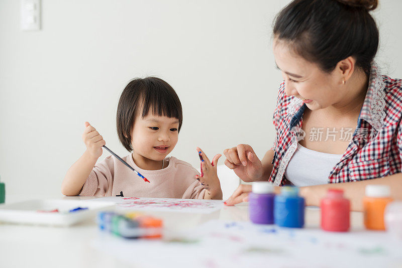 幸福的家庭是绘画。妈妈帮助她的女儿画画