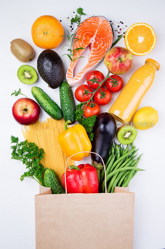 健康食品的背景。健康食品在满纸袋不同的产品鱼，蔬菜和水果在白色的背景