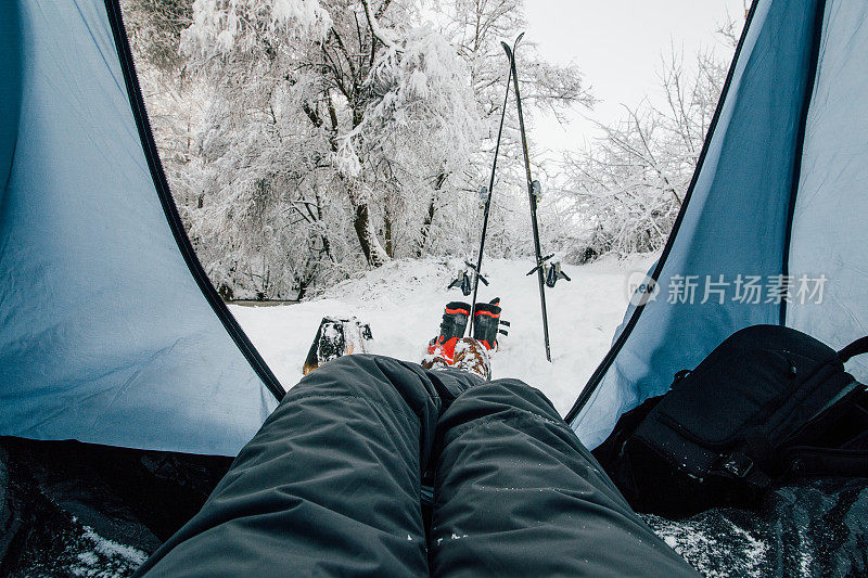 在冬季森林露营的人在帐篷外面带着滑雪装备