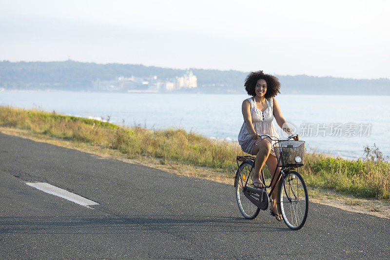 微笑的非洲妇女在海边骑车