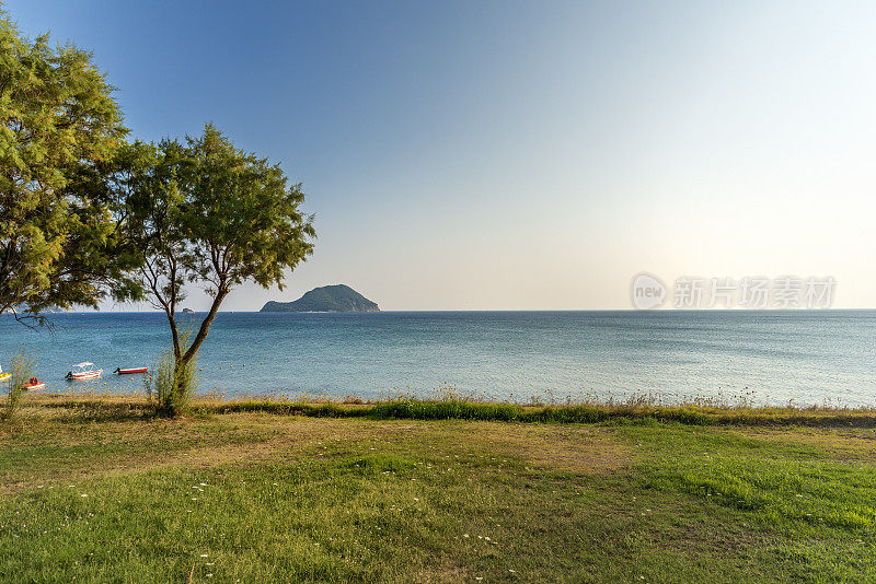 Zakinthos,贴水Sostis。在空旷的海滩上，一排带靠垫和阳伞的沙滩椅，在海龟岛(马拉松西)，清晨。GPS标记。