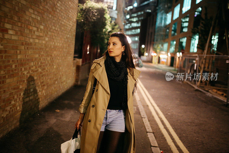 一个年轻的女人在晚上独自走在伦敦市中心的街道上