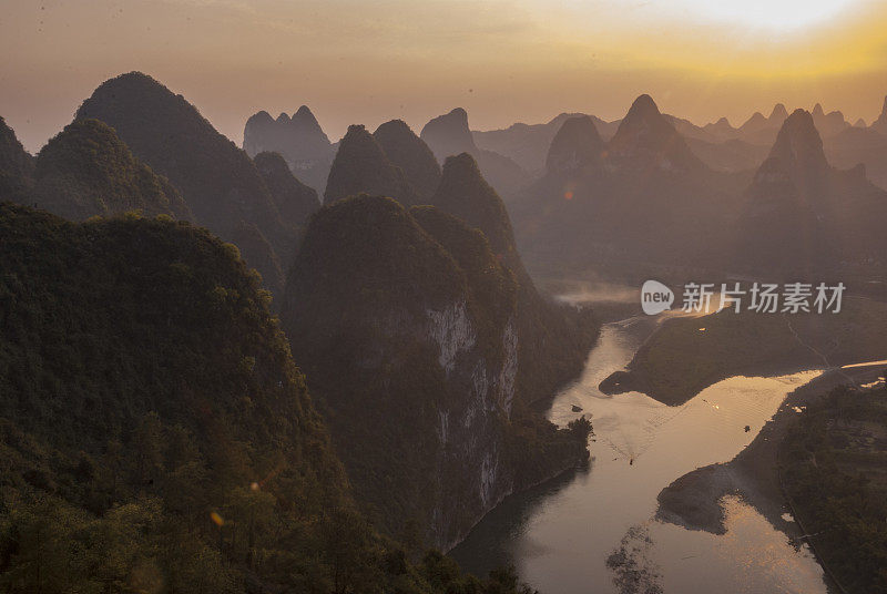 传统的中国日出景观与河流的水和不寻常的山脉热带森林沿海岸船明亮的阳光橙色的早晨天空